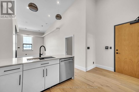 A modern kitchen with white cabinets and a wooden door.