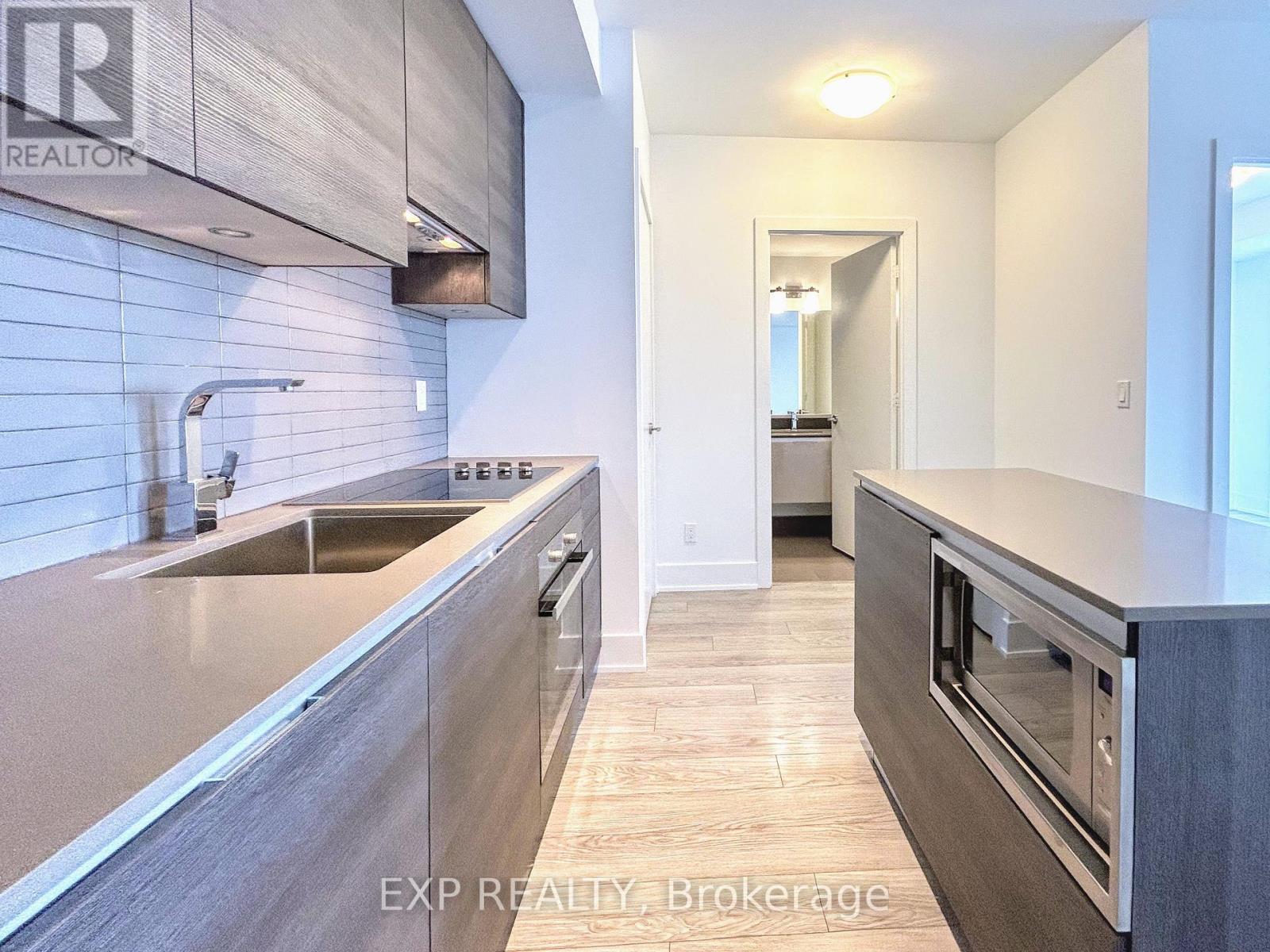 A modern kitchen with a sink and a stove top oven.