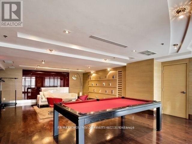 A pool table in a room with wood flooring and a white couch.