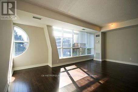 A spacious living room with a large window and wooden floors.