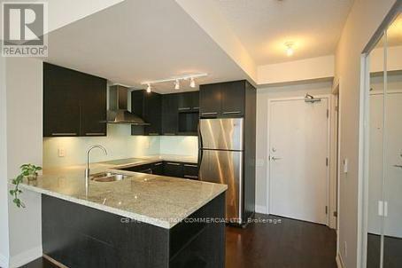A modern kitchen with a marble countertop and black cabinets.