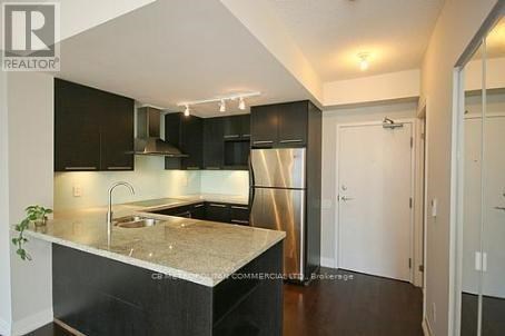 A modern kitchen with a marble countertop and black cabinets.