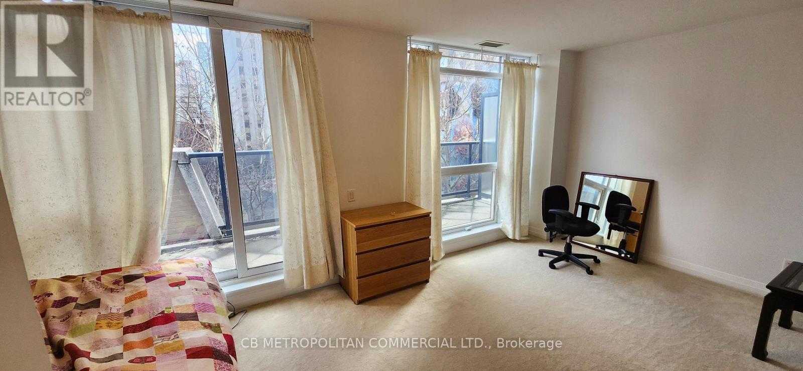 A bedroom with a bed, dresser, and chair in front of a window with curtains.