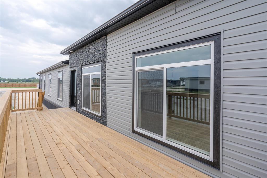 A grey house with a wooden deck and a glass door.