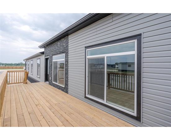 A grey house with a wooden deck and a glass door.