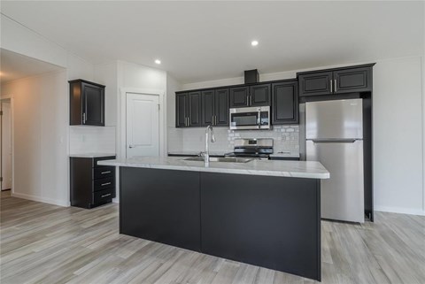 A modern kitchen with black cabinets and stainless steel appliances.