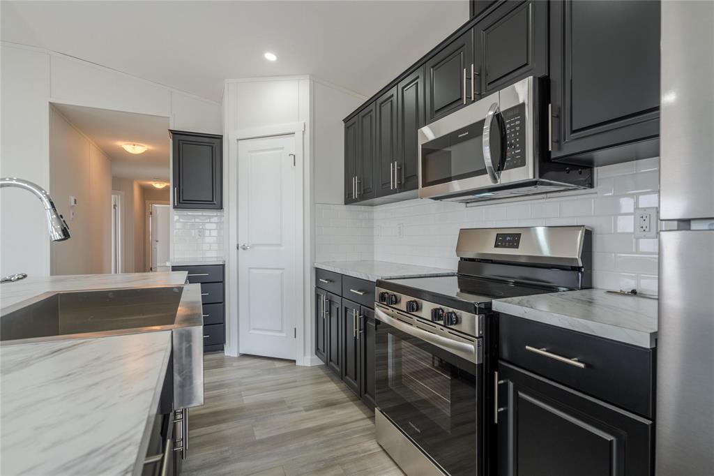 A modern kitchen with black cabinets and stainless steel appliances.
