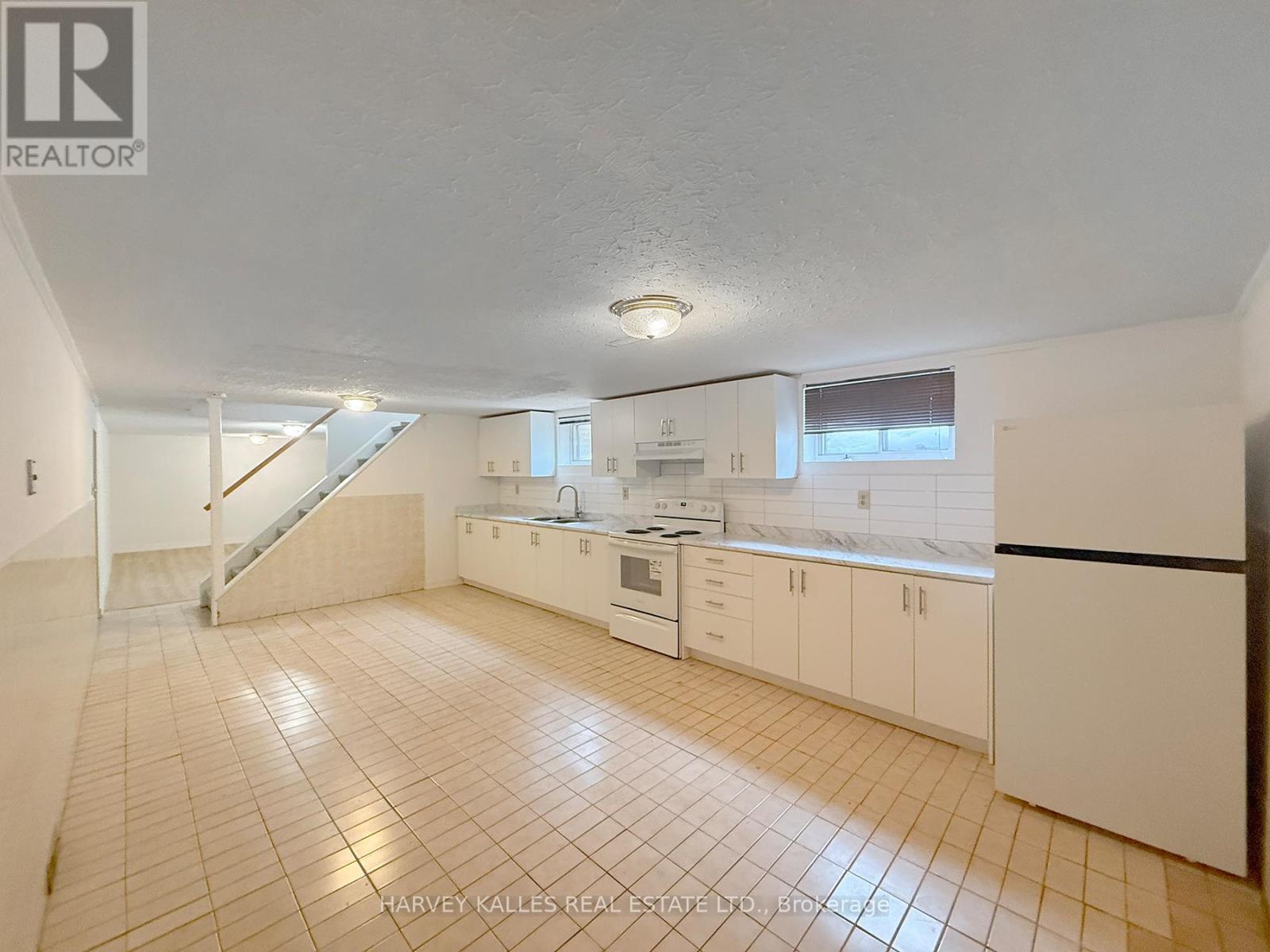 A kitchen with white cabinets and a tiled floor.