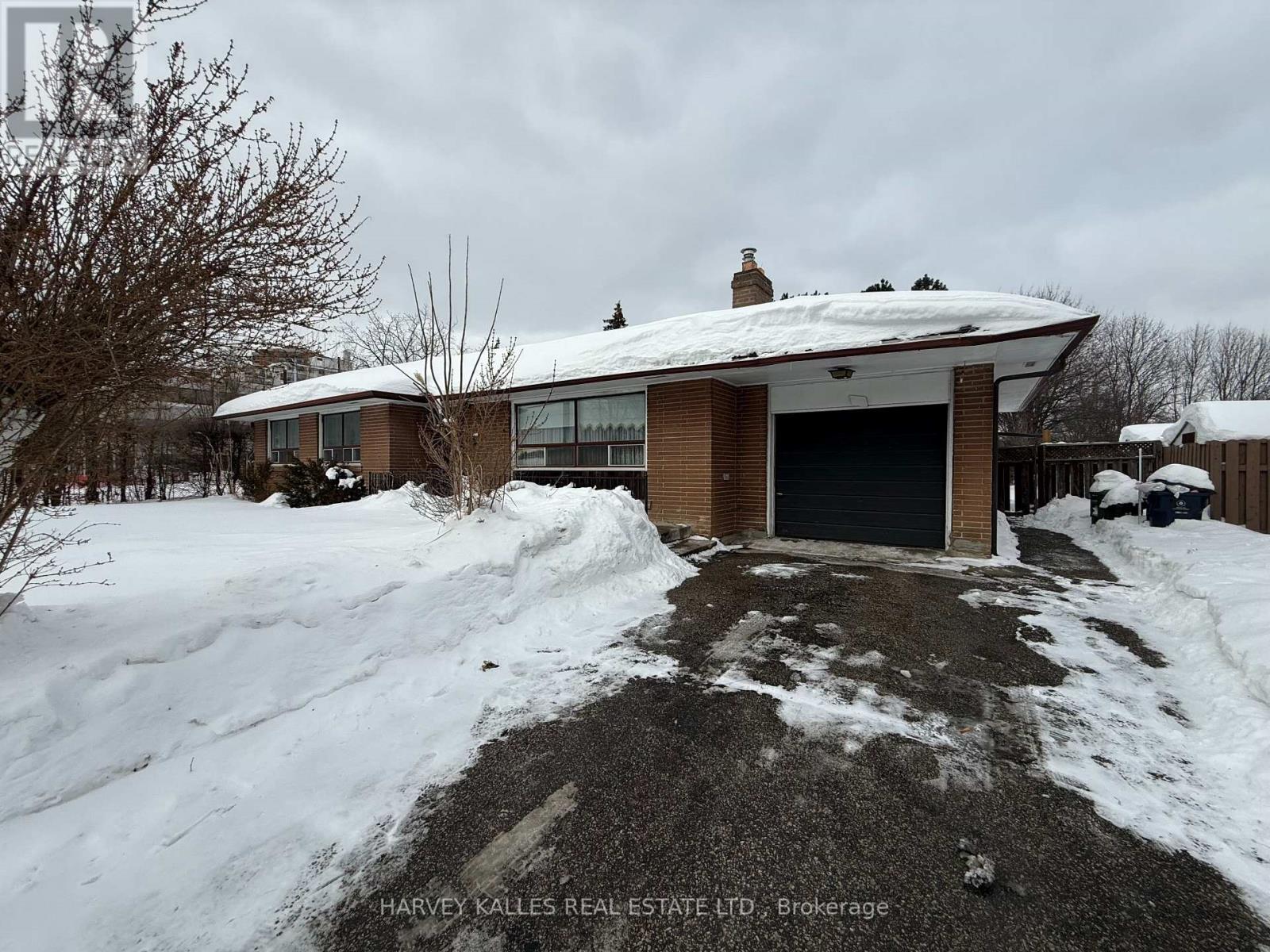 A snow-covered house with a driveway in front.