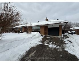 A snow-covered house with a driveway in front.