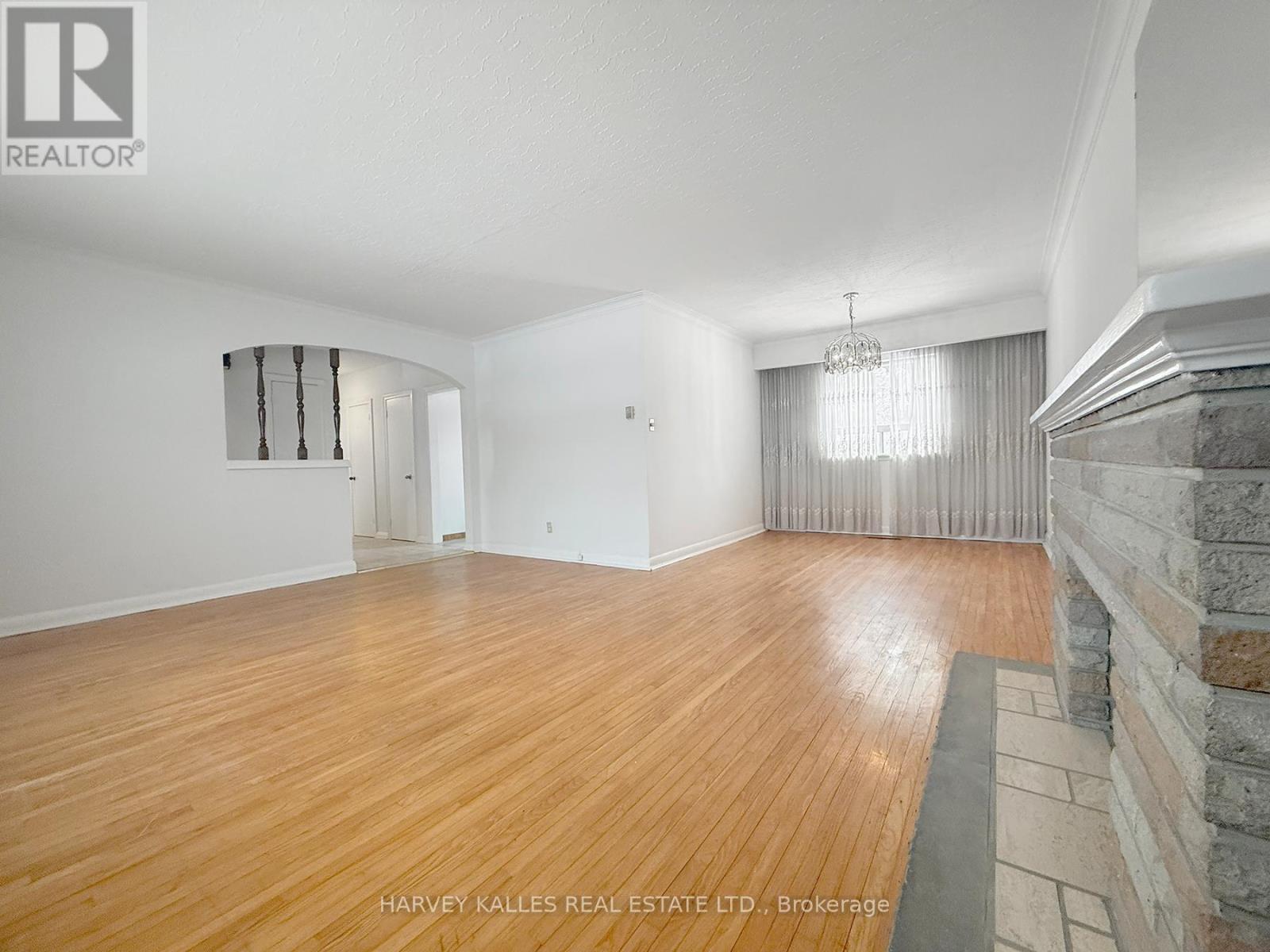 A spacious room with wooden flooring and a stone fireplace.
