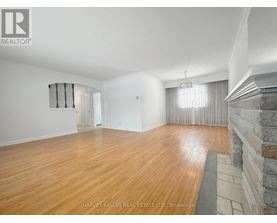A spacious room with wooden flooring and a stone fireplace.
