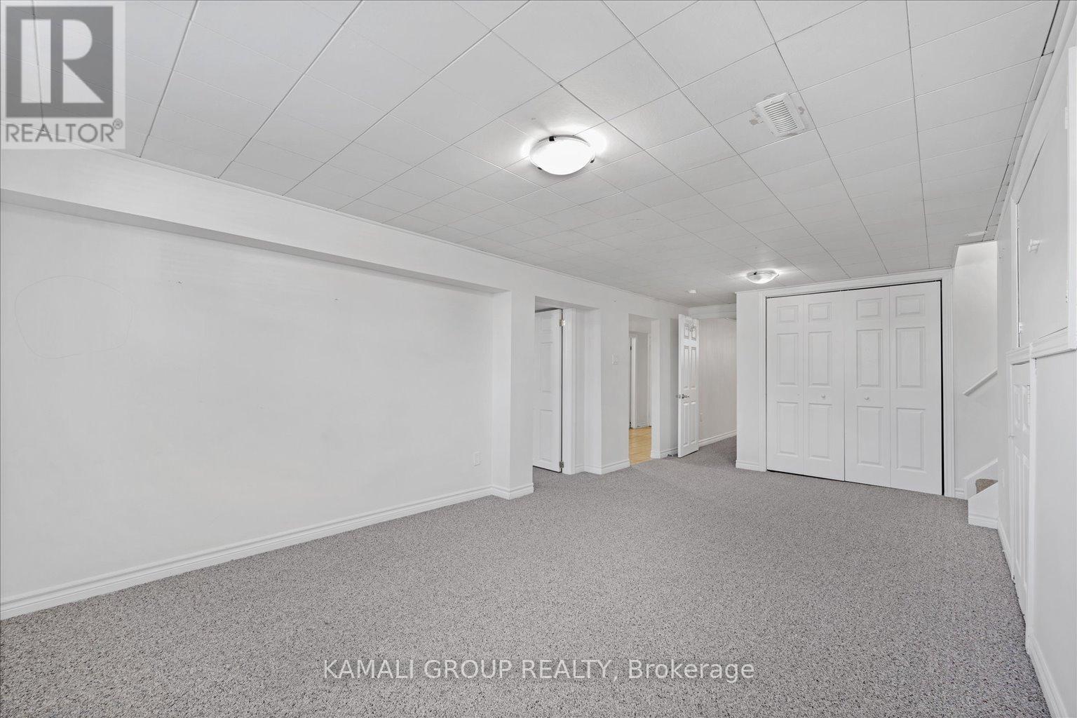 A spacious room with white walls and carpeted floor.