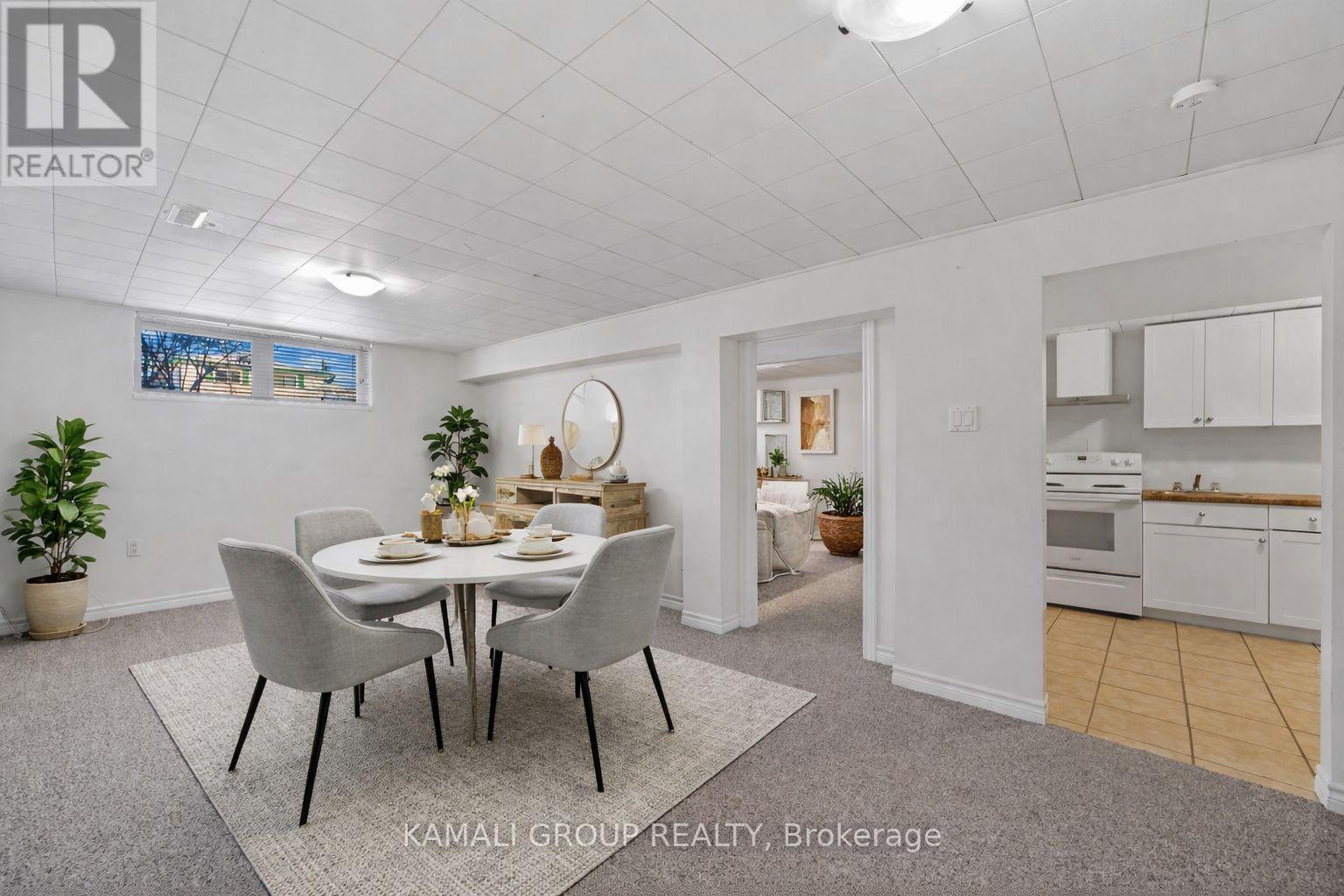 A dining room with a table set for four and a kitchen in the background.