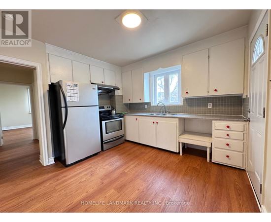 A kitchen with white cabinets and a black fridge.