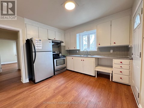 A kitchen with white cabinets and a black fridge.