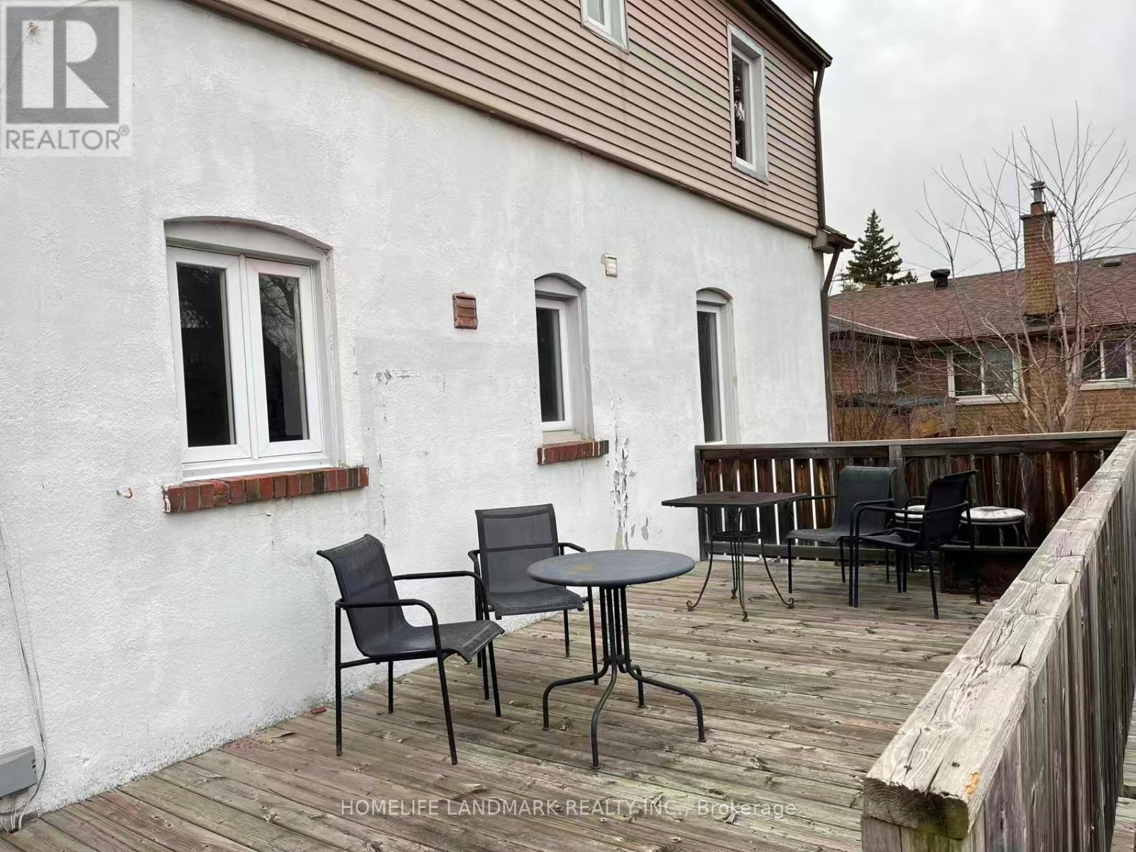 A white house with a wooden deck and patio furniture.
