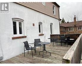 A white house with a wooden deck and patio furniture.