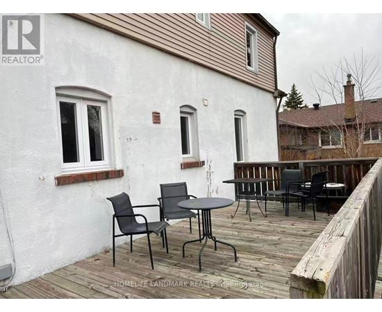 A white house with a wooden deck and patio furniture.
