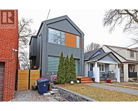 A modern house with a grey exterior and a small tree in front.