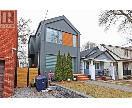 A modern house with a grey exterior and a small tree in front.