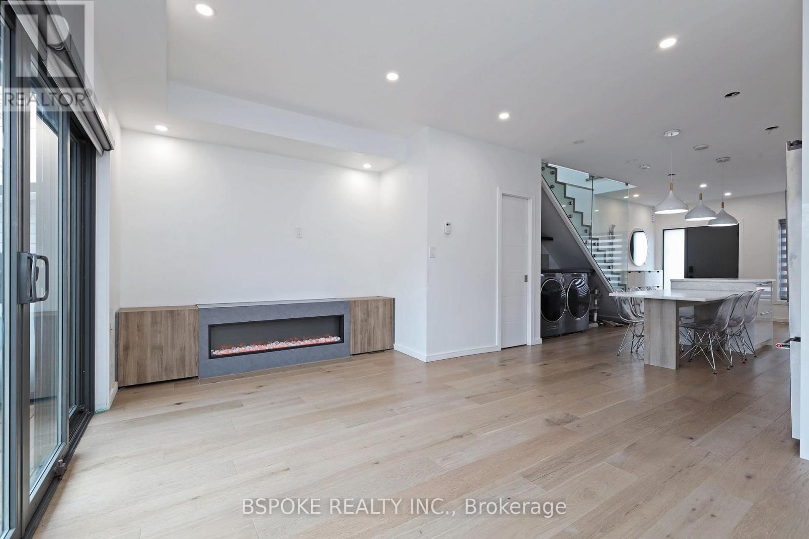 A modern living room with a fireplace and a dining area in the background.