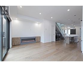 A modern living room with a fireplace and a dining area in the background.