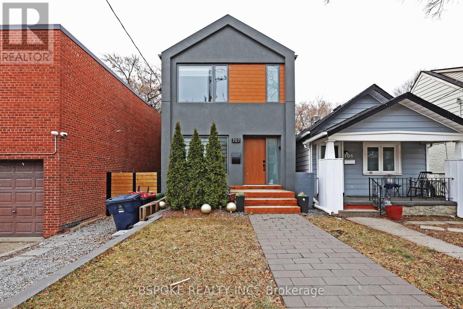 A house with a grey front and a red brick wall to the left.