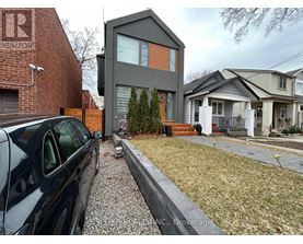 A house with a grey front and a red brick wall to the left.
