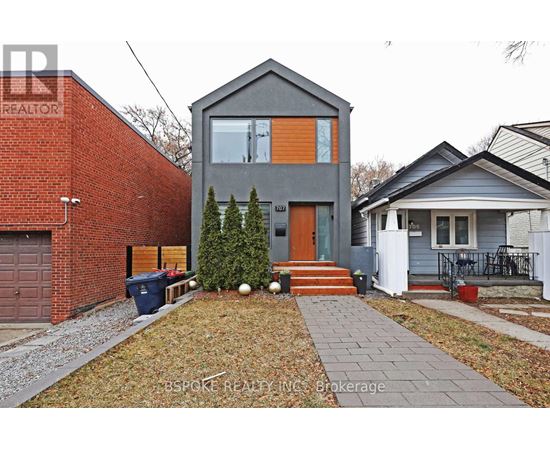 A house with a grey front and a red brick wall to the left.