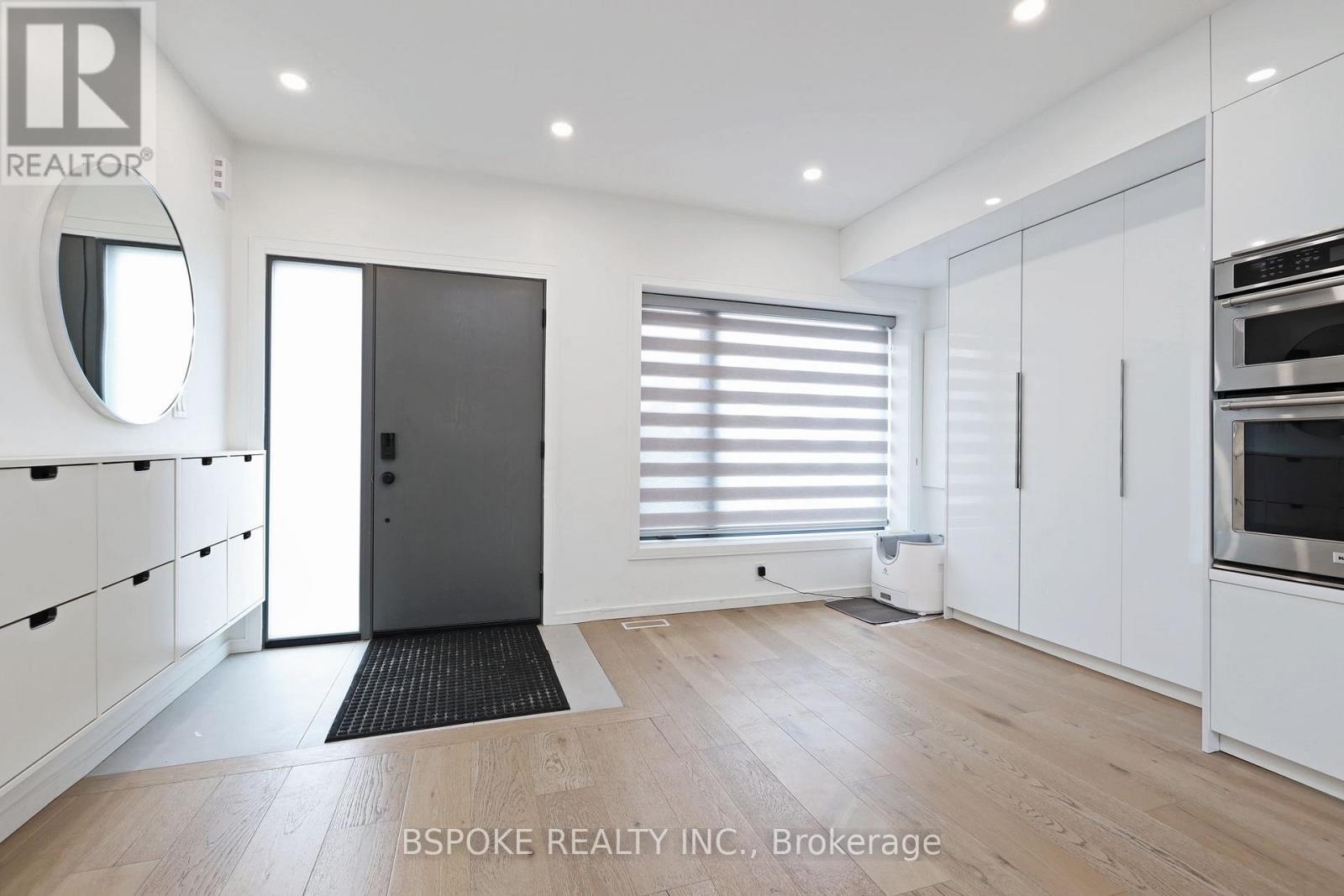 A modern kitchen with white cabinets and a black door.