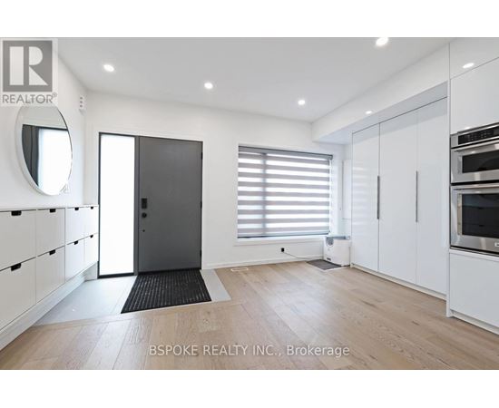 A modern kitchen with white cabinets and a black door.