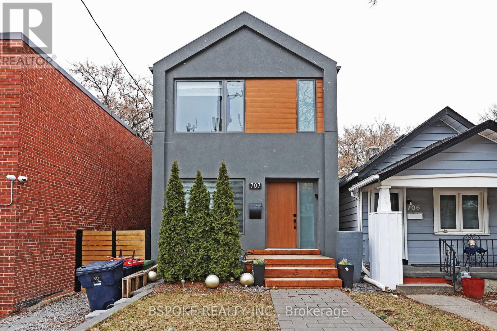A modern house with a grey exterior and a brown door is shown.