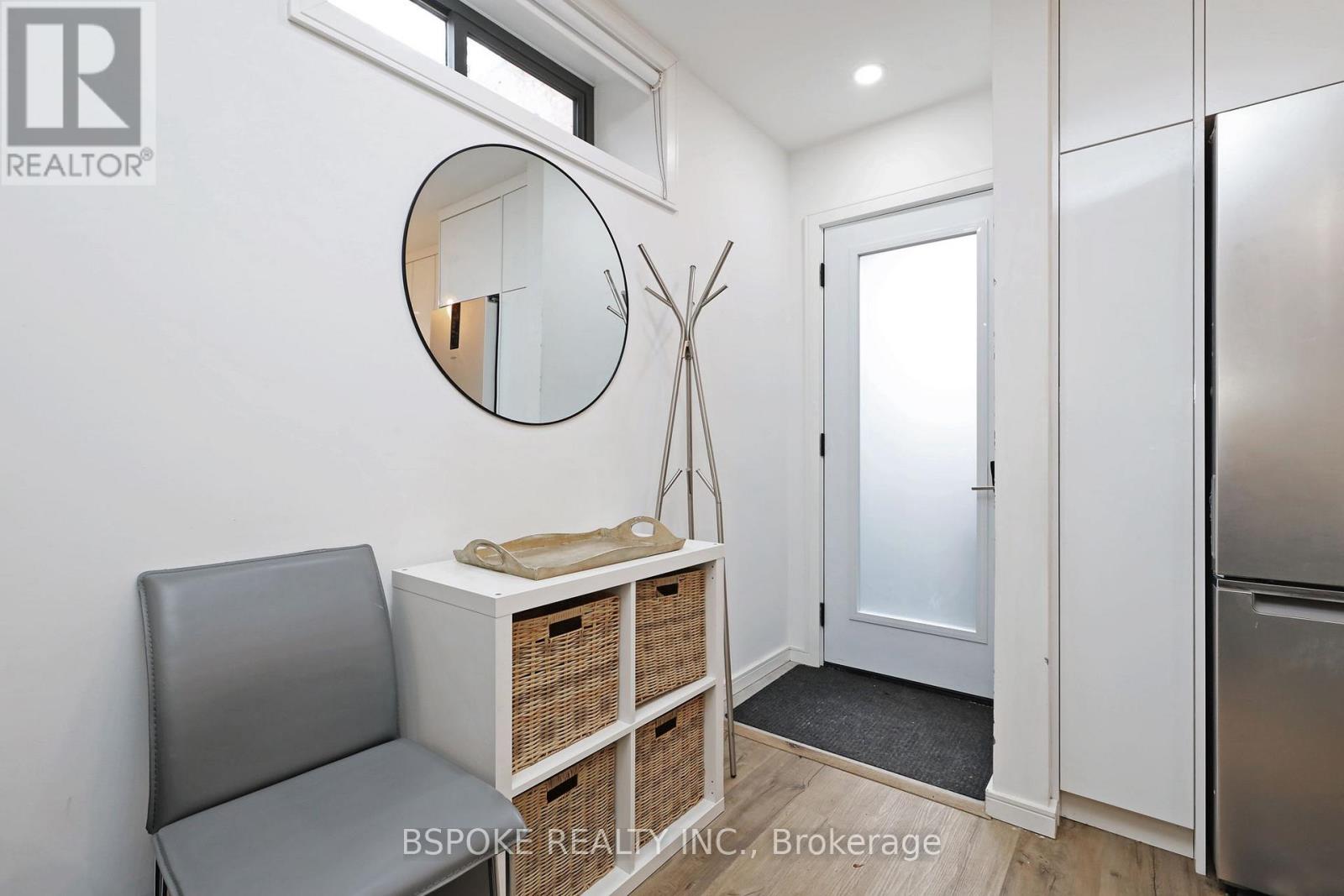 A modern kitchen with a grey chair and a round mirror on the wall.