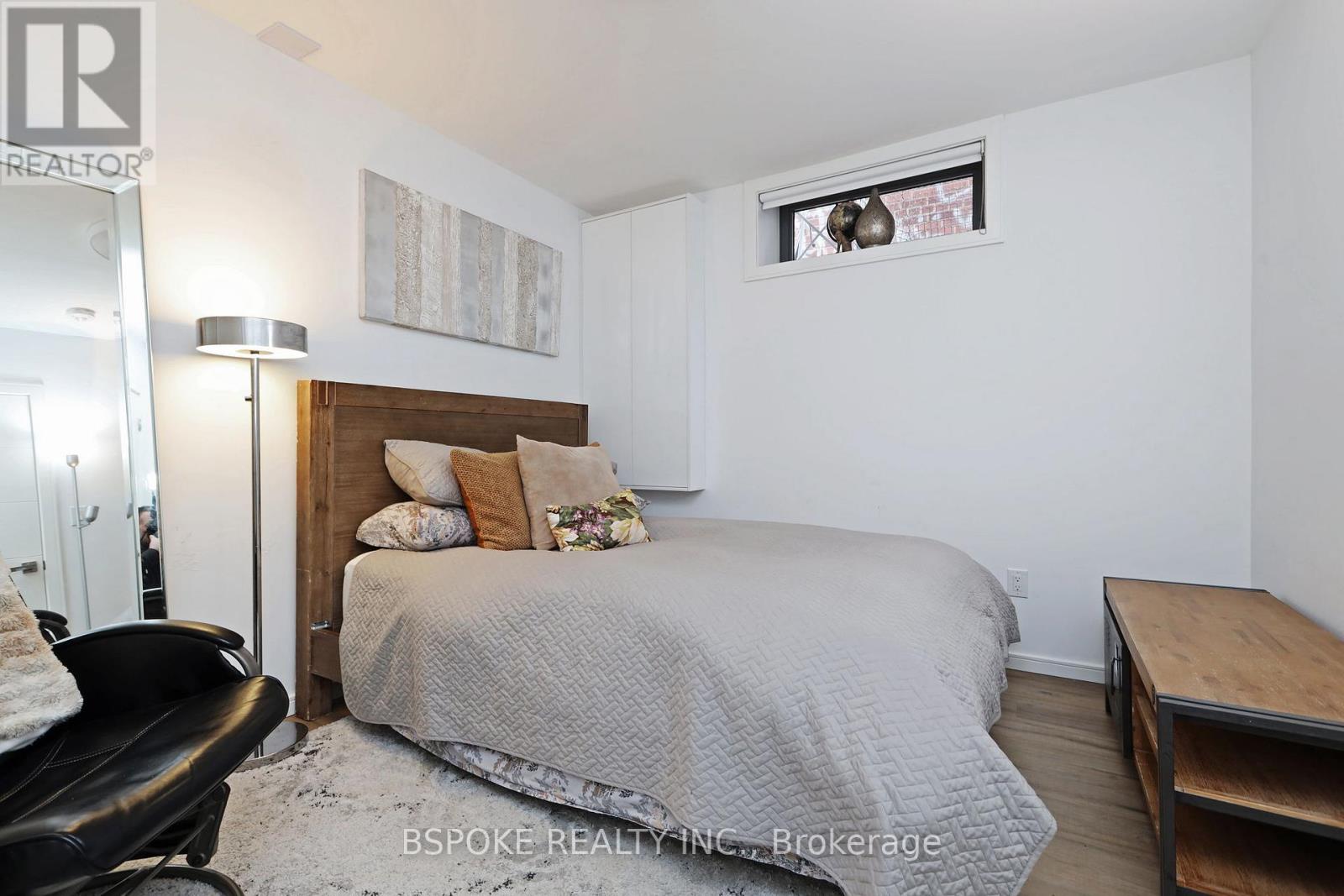 A bedroom with a bed, chair, and a painting on the wall.