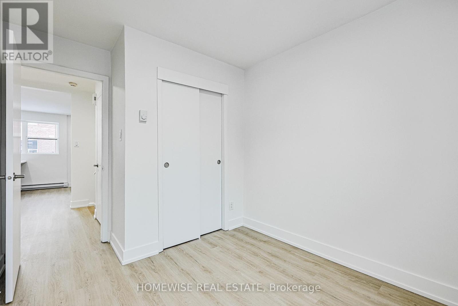 A white bedroom with a door and a window.