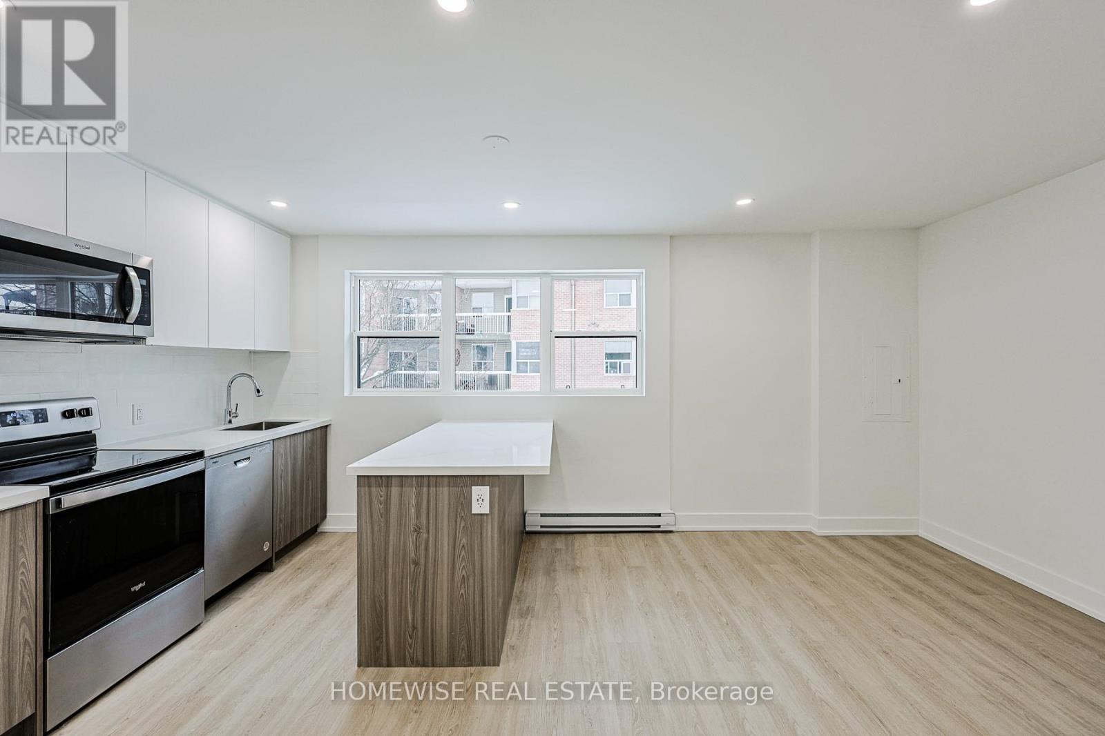 A kitchen with white cabinets and a window with a view of a building.