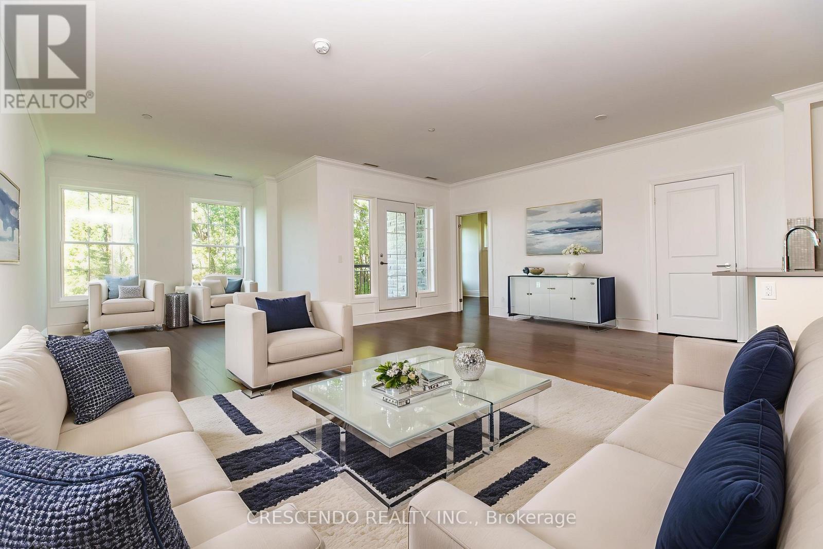 A living room with white furniture and a glass coffee table.
