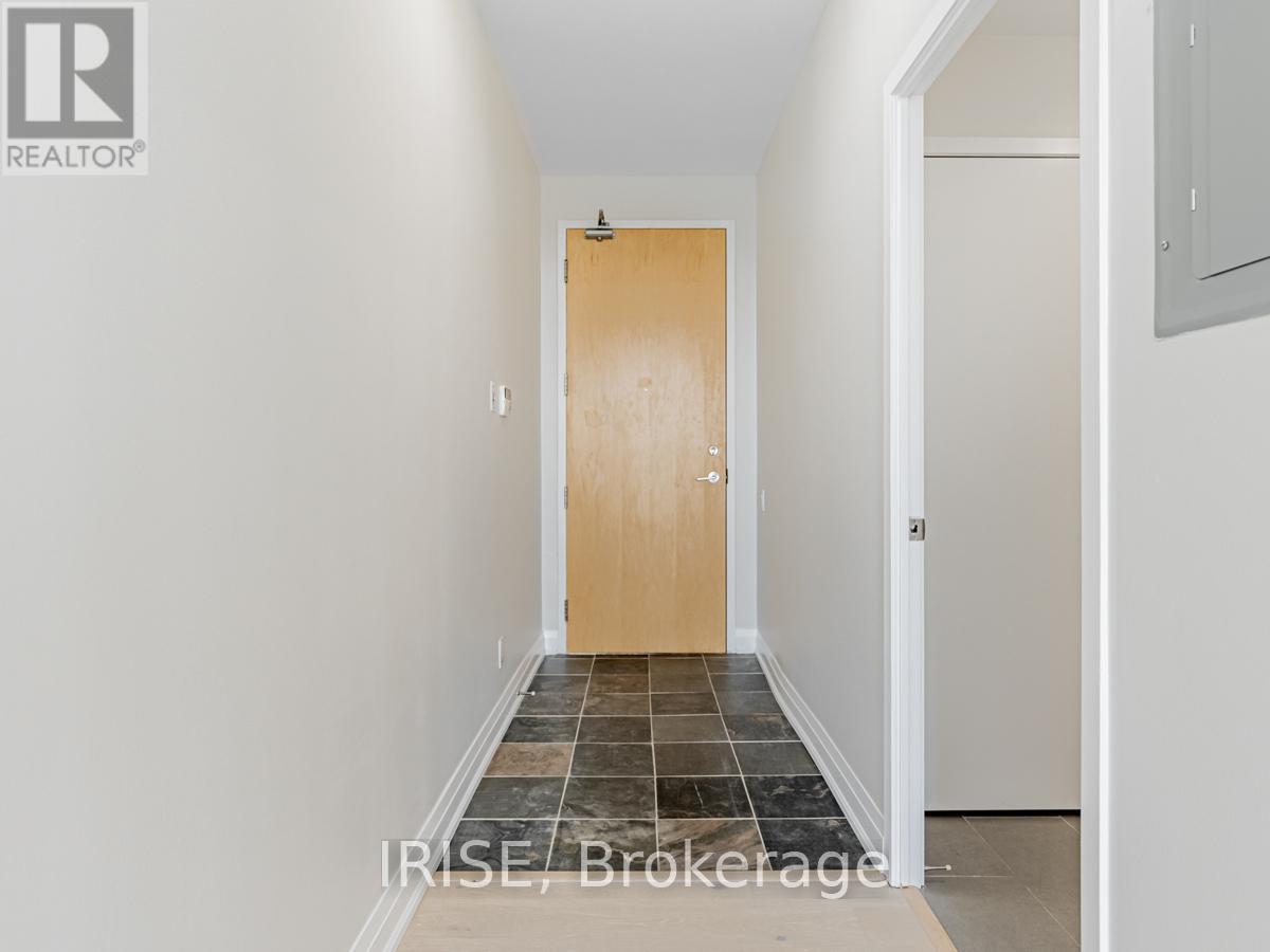 A hallway with a wooden door and tiled floor.