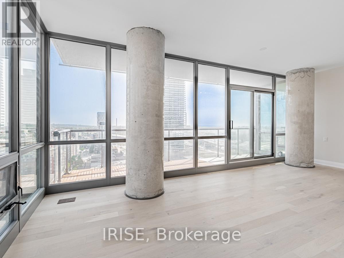 A spacious room with large windows and two concrete pillars.
