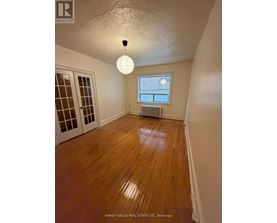 A room with wooden floors and a window with blinds.