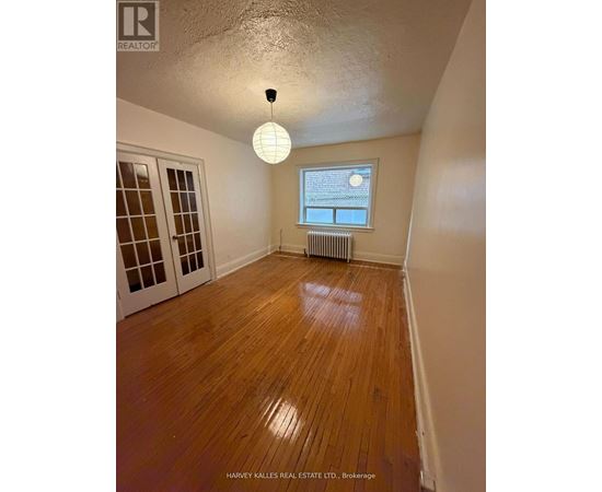 A room with wooden floors and a window with blinds.