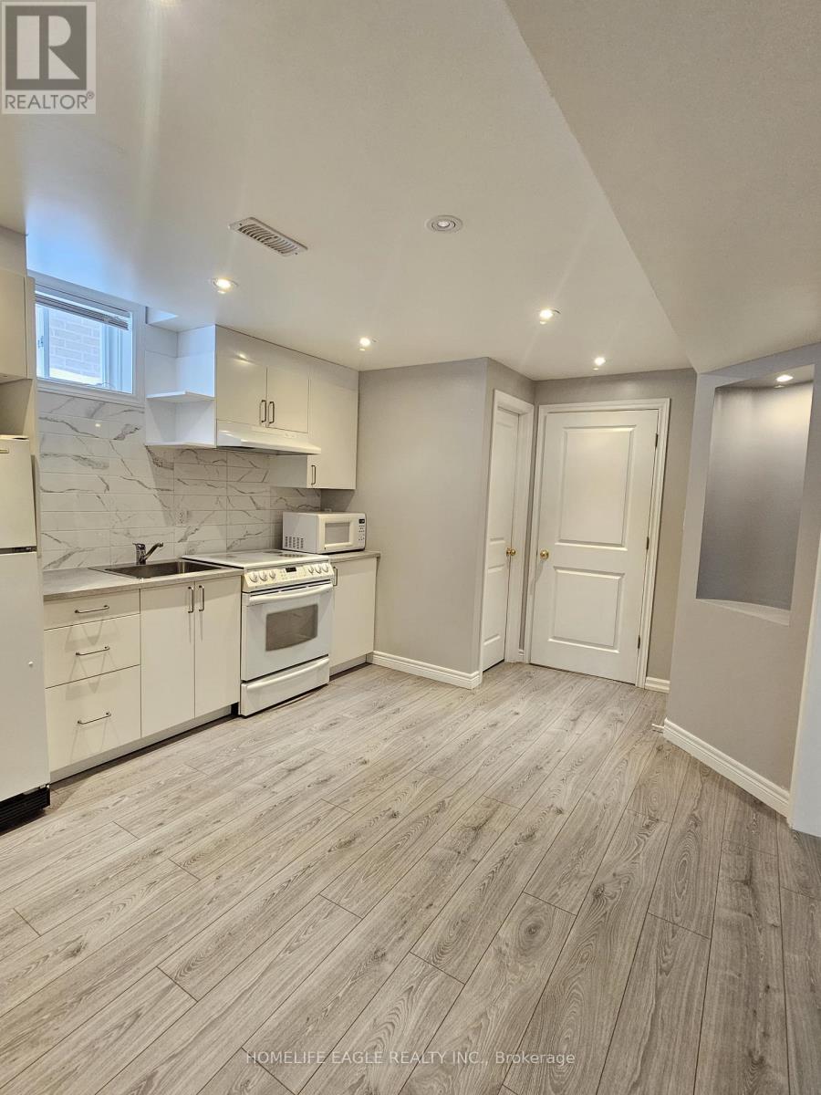 A well-lit kitchen with wooden flooring and white appliances.