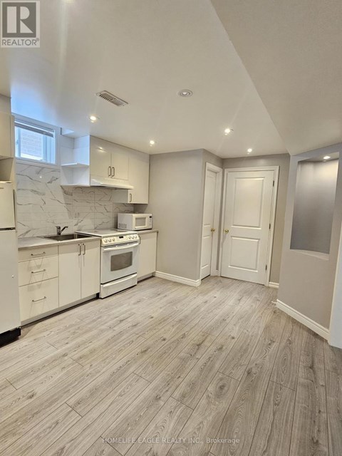 A well-lit kitchen with wooden flooring and white appliances.