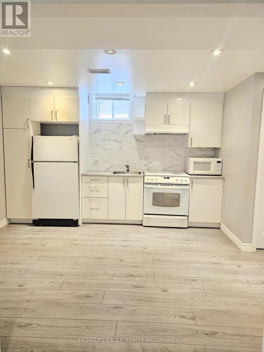 A white kitchen with a refrigerator, oven, microwave, and cabinets.