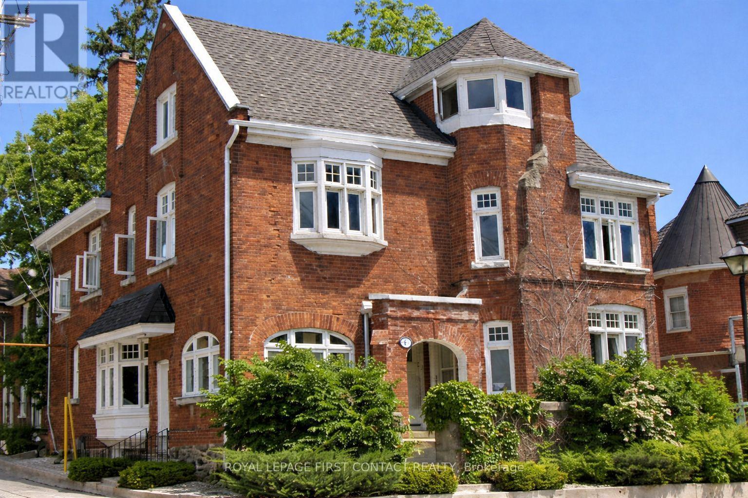 A large red brick house with a black roof and white windows.
