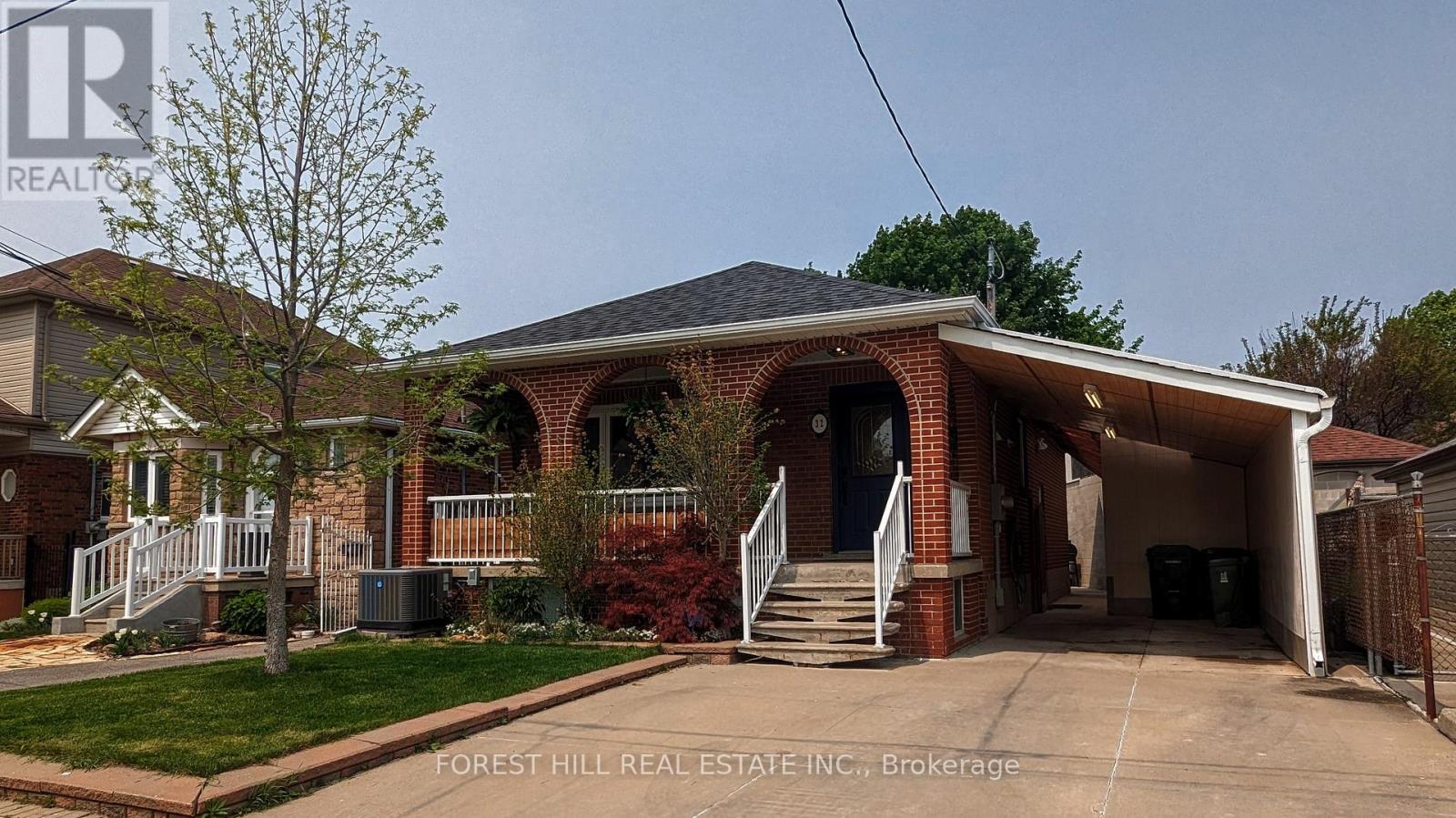 A house with a garage and a tree in front of it.
