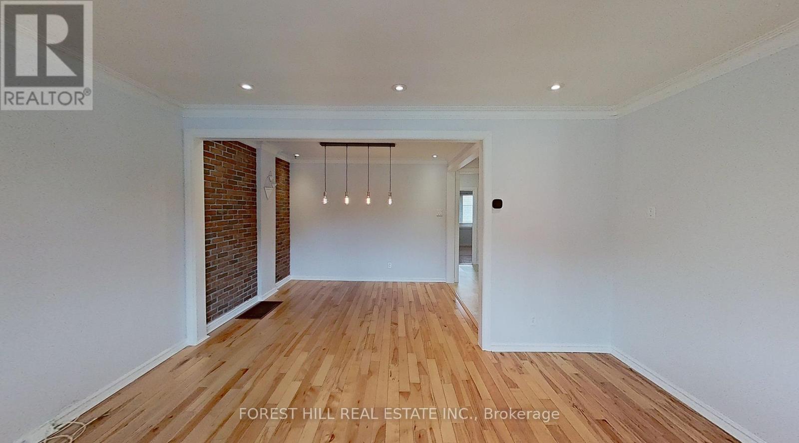 A spacious room with wooden flooring and a brick wall.