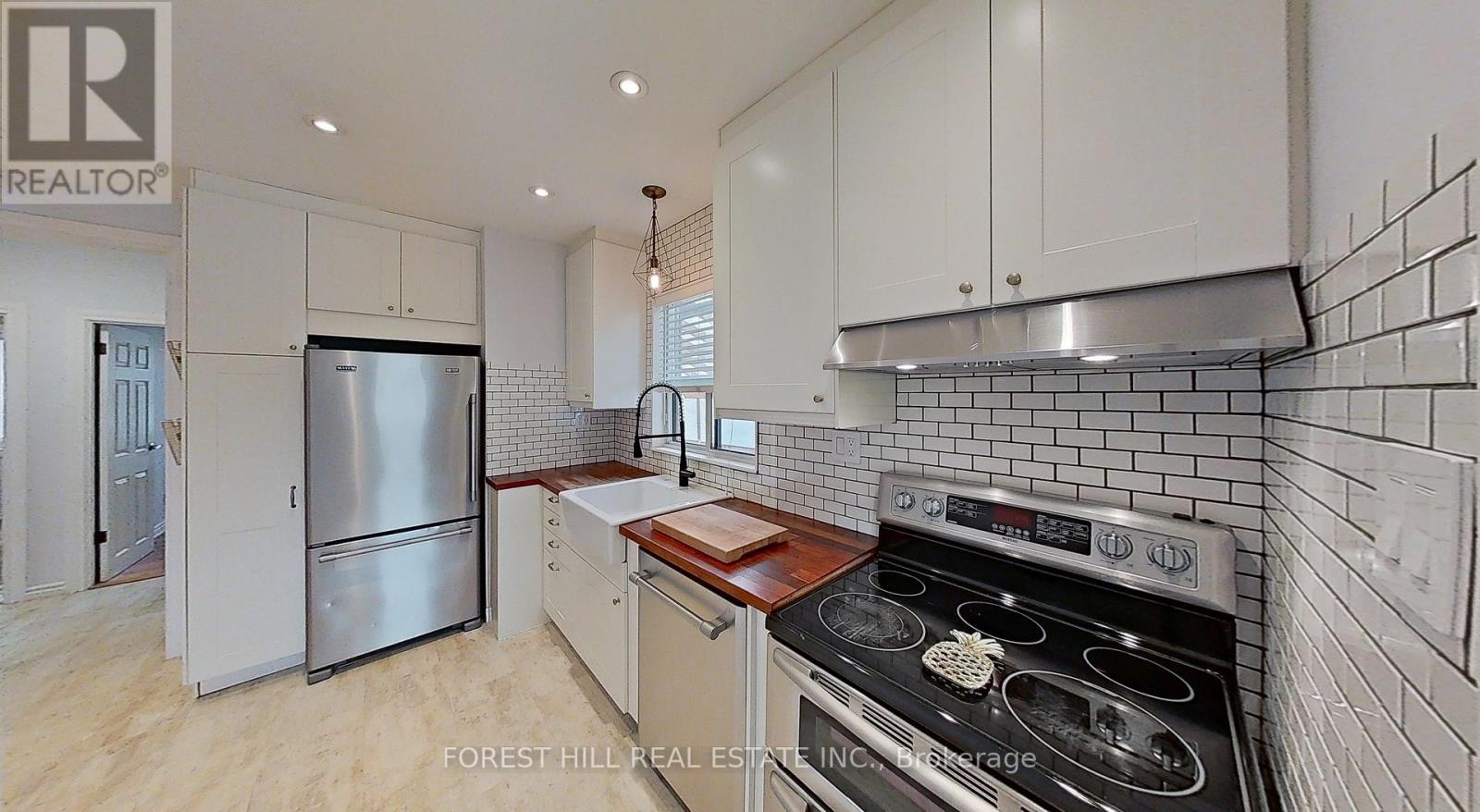 A modern kitchen with a stainless steel refrigerator and a black stove top oven.