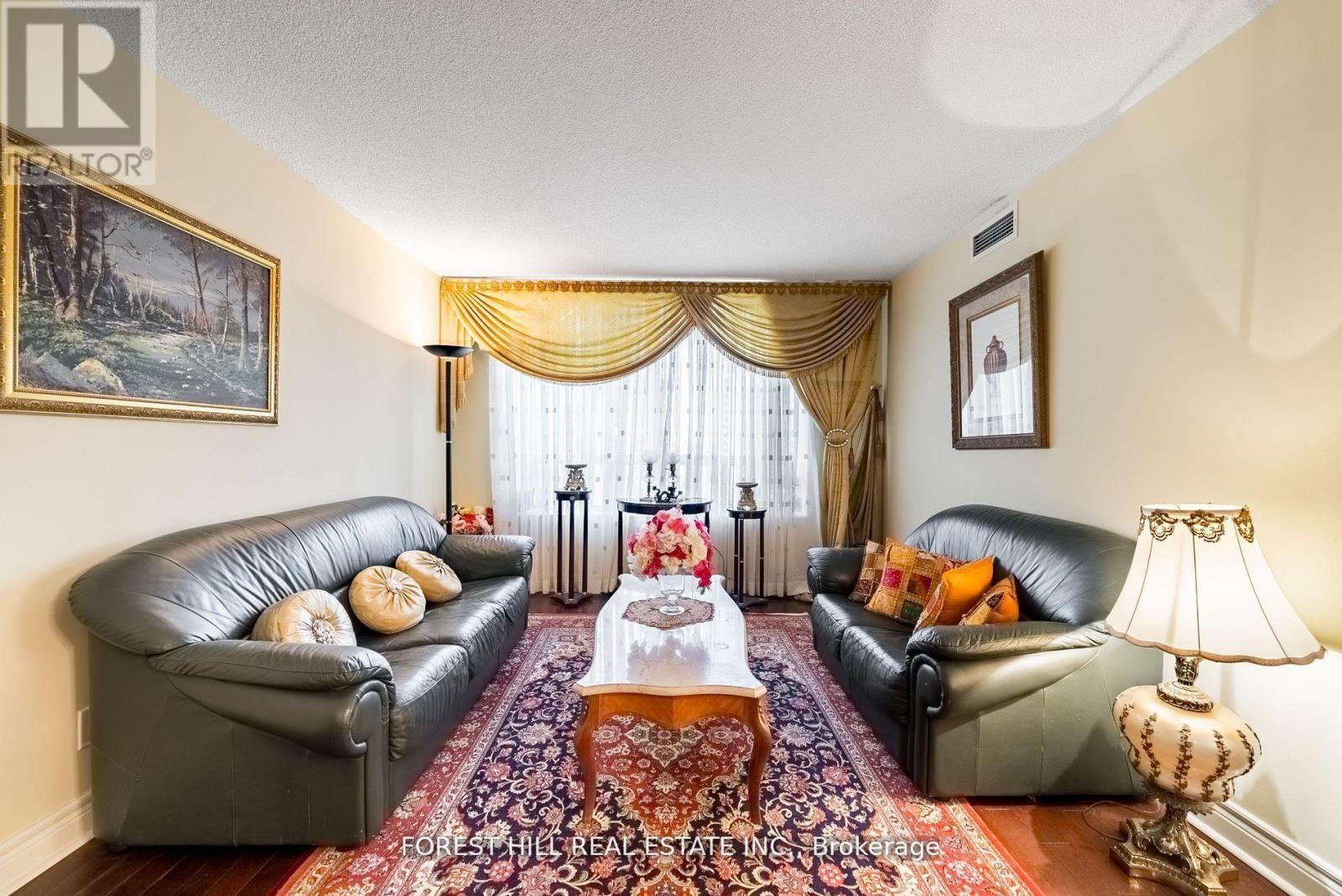 A living room with a black leather couch, a coffee table, and a painting on the wall.